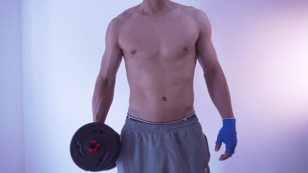 Muscular man doing dumbbell exercise on his right arm