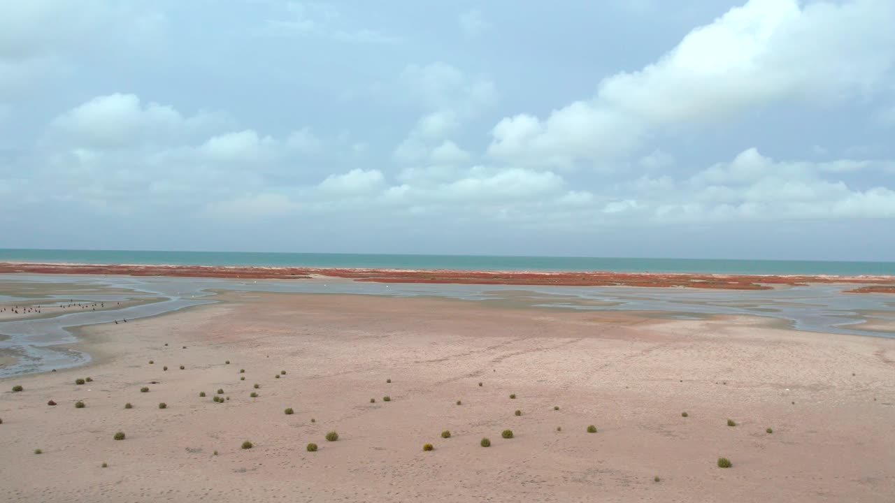 drone aéreo deslizándose sobre la pintoresca y pintoresca playa hawaiana con un vasto paisaje marino que se extiende en el horizonte bajo un dramático cielo nublado durante un día soleado