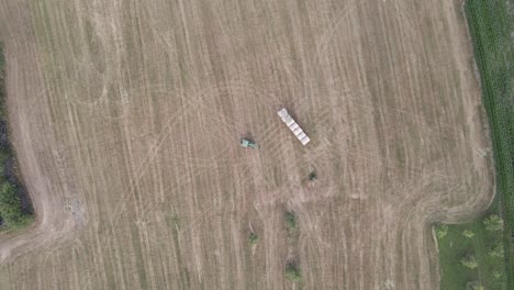 Toma-Aérea-Superior-De-Un-Tractor-Depositando-Un-Fardo-De-Heno-En-Un-Campo-En-Francia