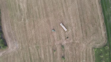 toma aérea superior de un tractor depositando una bala de heno en un campo en francia