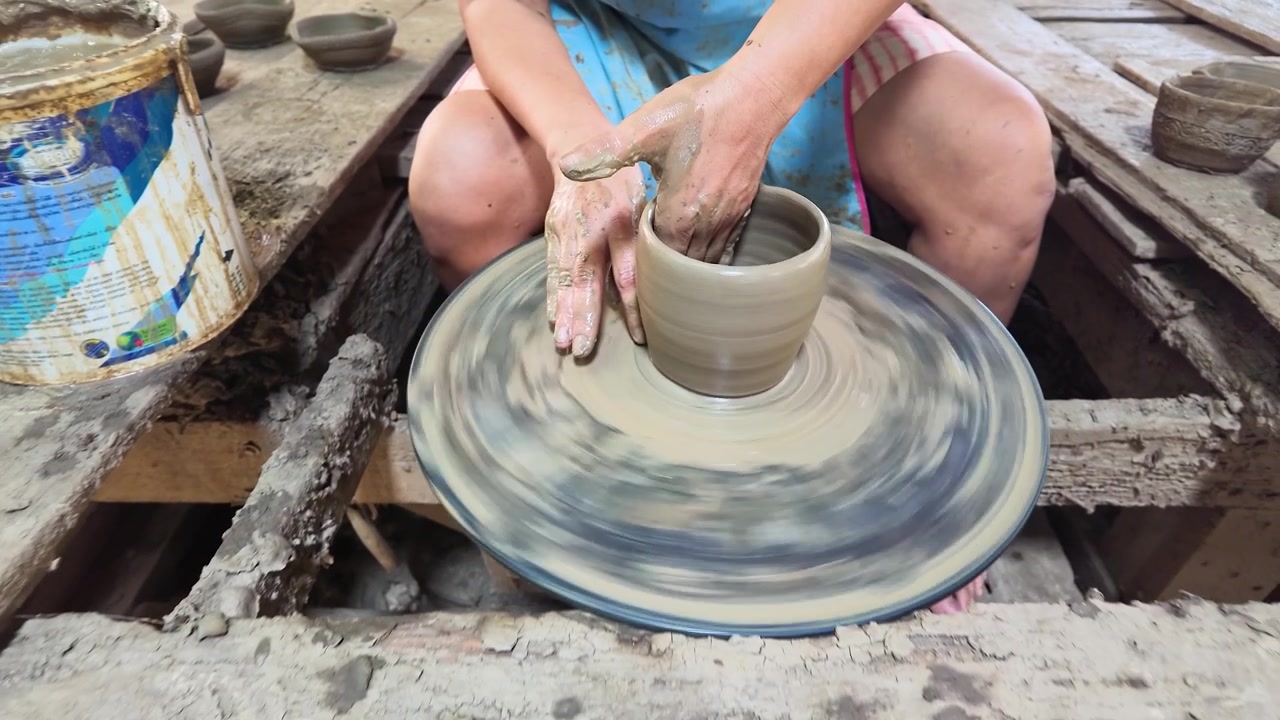 Mani esperte modellano argilla bagnata su un tornio in un laboratorio di Koh Kret, Thailandia