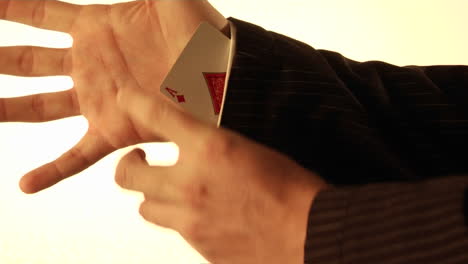 a  man tucks a playing card into his shirt sleeve