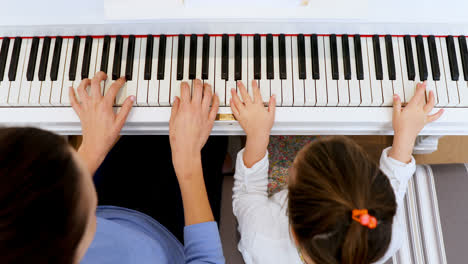 mother assisting daughter in playing piano 4k