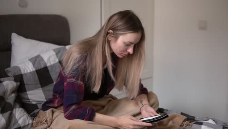 concentrated woman in the morning sitting in bed surfing internet using tablet