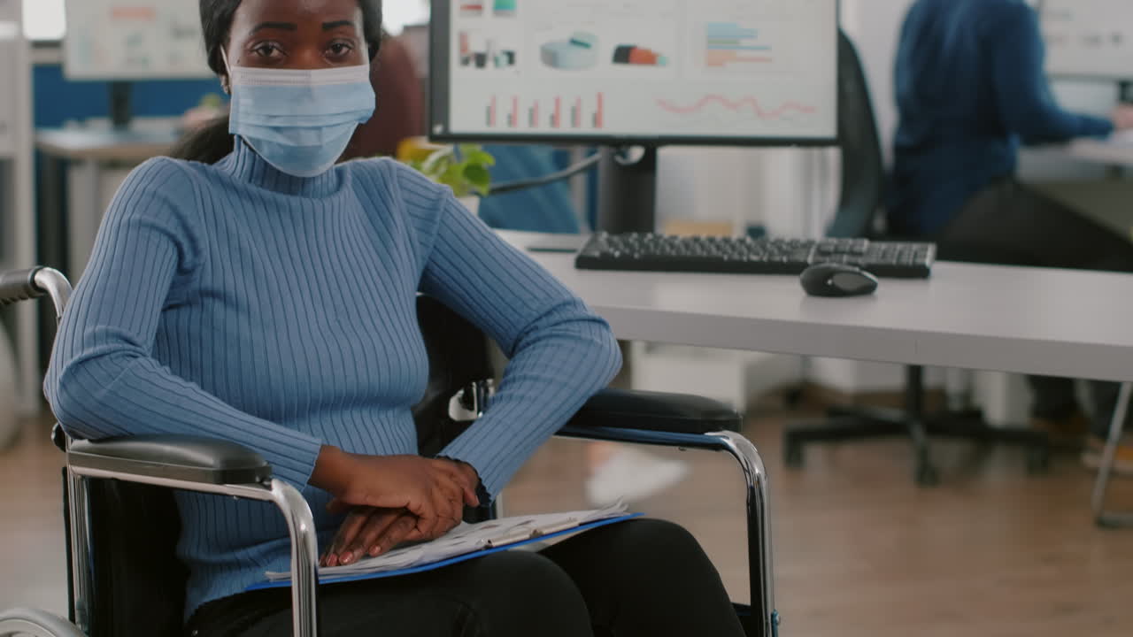 Project manager nero con disabilità che indossa una maschera facciale che guarda la telecamera
