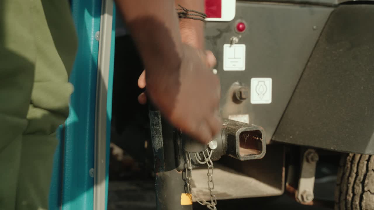 African American man tightening trailer hitch to car for towing