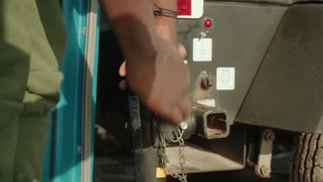hombre afroamericano apretando el enganche del remolque al coche para remolcar