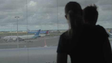 madre e hijo mirando por la ventana del aeropuerto