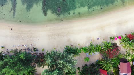 Paradise-exotic-beach-with-white-sand-washed-by-colorful-lagoon-with-coral-reefs-on-tropical-island-with-vacations-resorts-in-Thailand