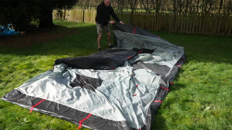 a man packing away a tent folding it up