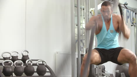 Joven-Trabajando-Con-Cuerdas-De-Batalla-En-Un-Gimnasio,-ángulo-Bajo