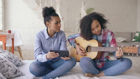 mother and daughter learning guitar together