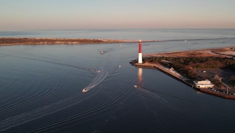 Vista-Aérea-De-Drones-De-Barcos-Que-Se-Mueven-Alrededor-Del-Faro-De-Barnegat-Al-Atardecer