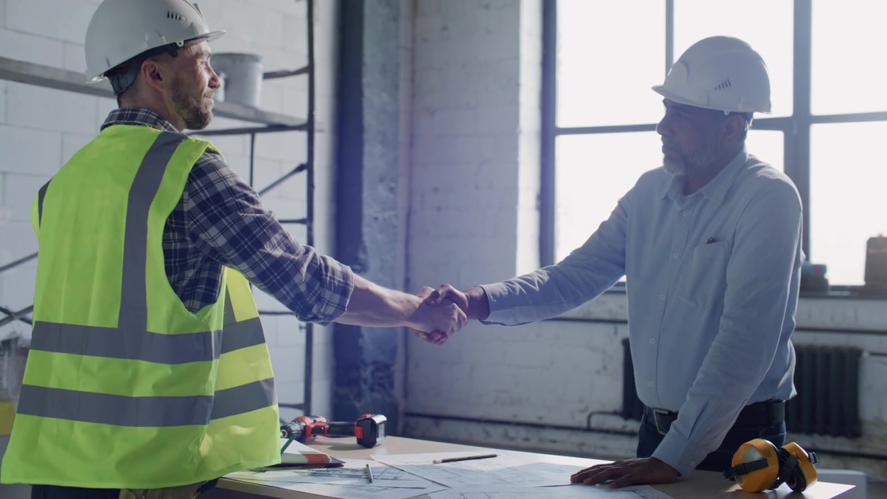 Engenheiro-chefe e empreiteiro apertando as mãos após chegar a um acordo no local da obra
