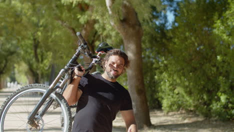 hombre con discapacidad levantando una bicicleta y mostrando el signo de shakah