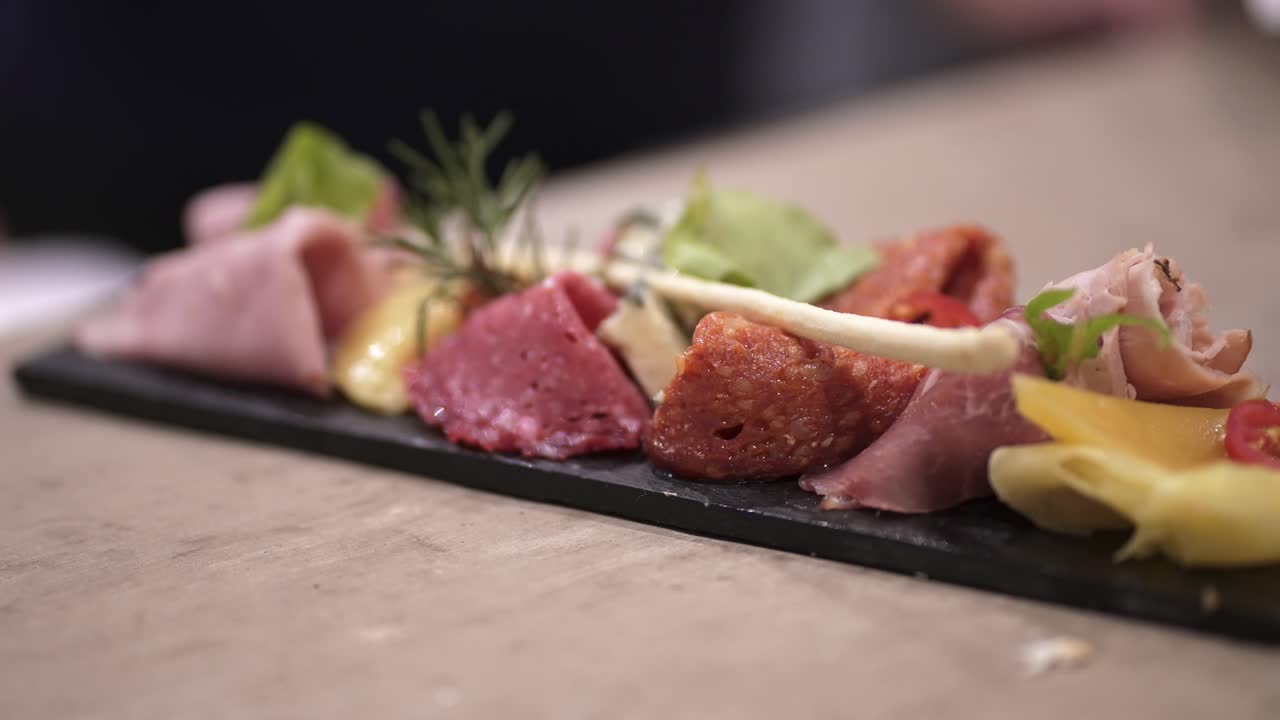 A selection of cured meats (salami, ham) and various cheeses, seasoned with rosemary, ready for a wine-tasting or party