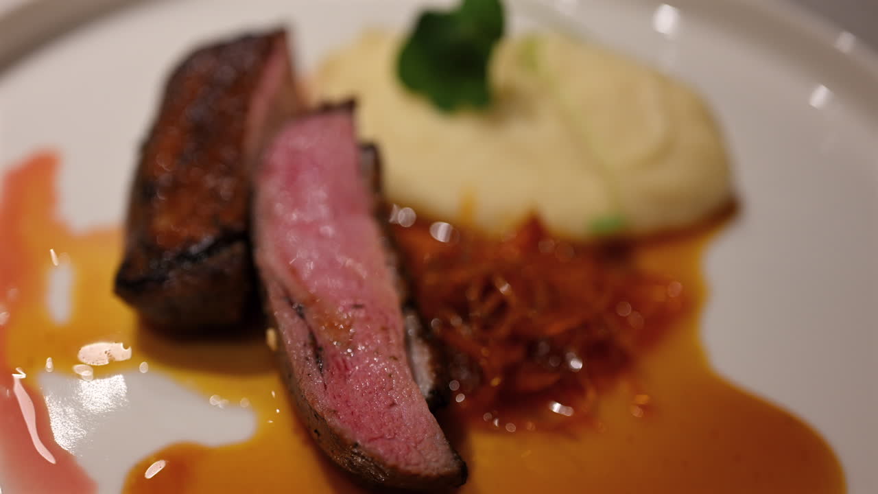 Fette d'anatra da alta cucina servite con una purea cremosa e una salsa ricca su un piatto elegante.