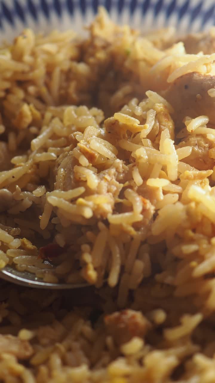 Primo piano di un cucchiaio che raccoglie delizioso pollo e riso