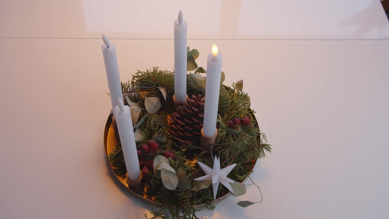 Lit advent wreath with candles and festive winter decorations on a table