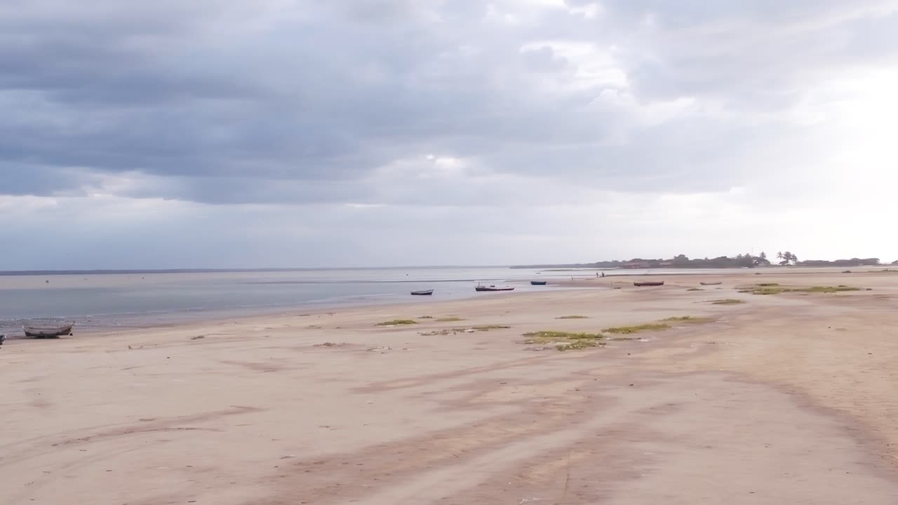 imágenes aéreas de drones capturan una playa de arena húmeda durante la marea baja en colombia, con una impresionante puesta de sol en el fondo y algunos barcos estacionados en la arena