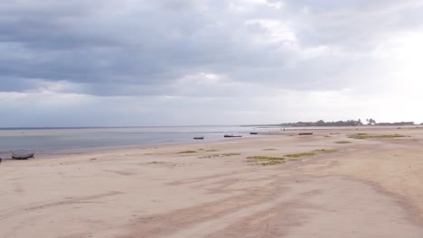 Imágenes-Aéreas-De-Drones-Capturan-Una-Playa-De-Arena-Húmeda-Durante-La-Marea-Baja-En-Colombia,-Con-Una-Impresionante-Puesta-De-Sol-De-Fondo-Y-Algunos-Barcos-Estacionados-En-La-Arena.