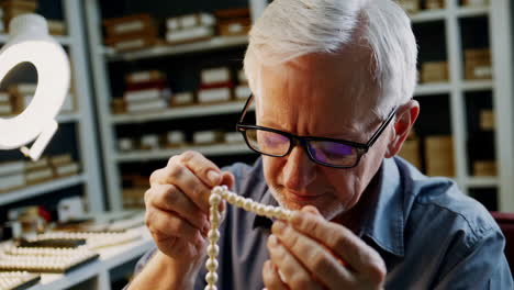 senior jeweler carefully crafting a pearl necklace