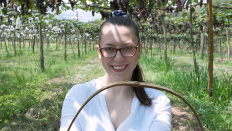 Close-up-shot-of-withe-Basket-full-of-red-grapes-held-by-Smiling-brunette-woman,-Brazilian-Vineyard