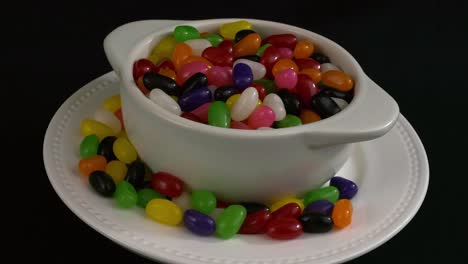 Assorted-bright,-sweet-Jelly-beans-in-bowl-rotate-on-black-background