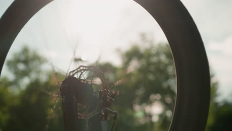 close-up of bicycle wheel rotating fast with sunlight reflecting off the metal, creating a beautiful, dynamic effect as the wheel spins, surrounded by a blurred background of greenery