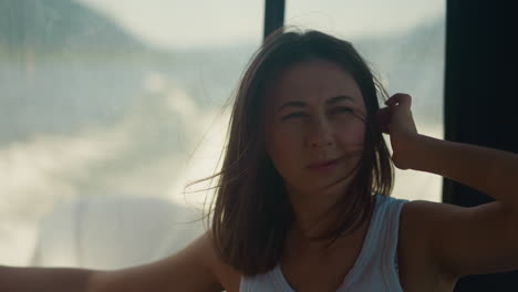 thoughtful woman adjusts messy hair riding fast motorboat at sea resort. lady silhouette sits in cabin of modern yacht at water trip. passenger in boat