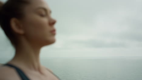 mujer atractiva relajándose día nublado de cerca. chica meditando en la costa.