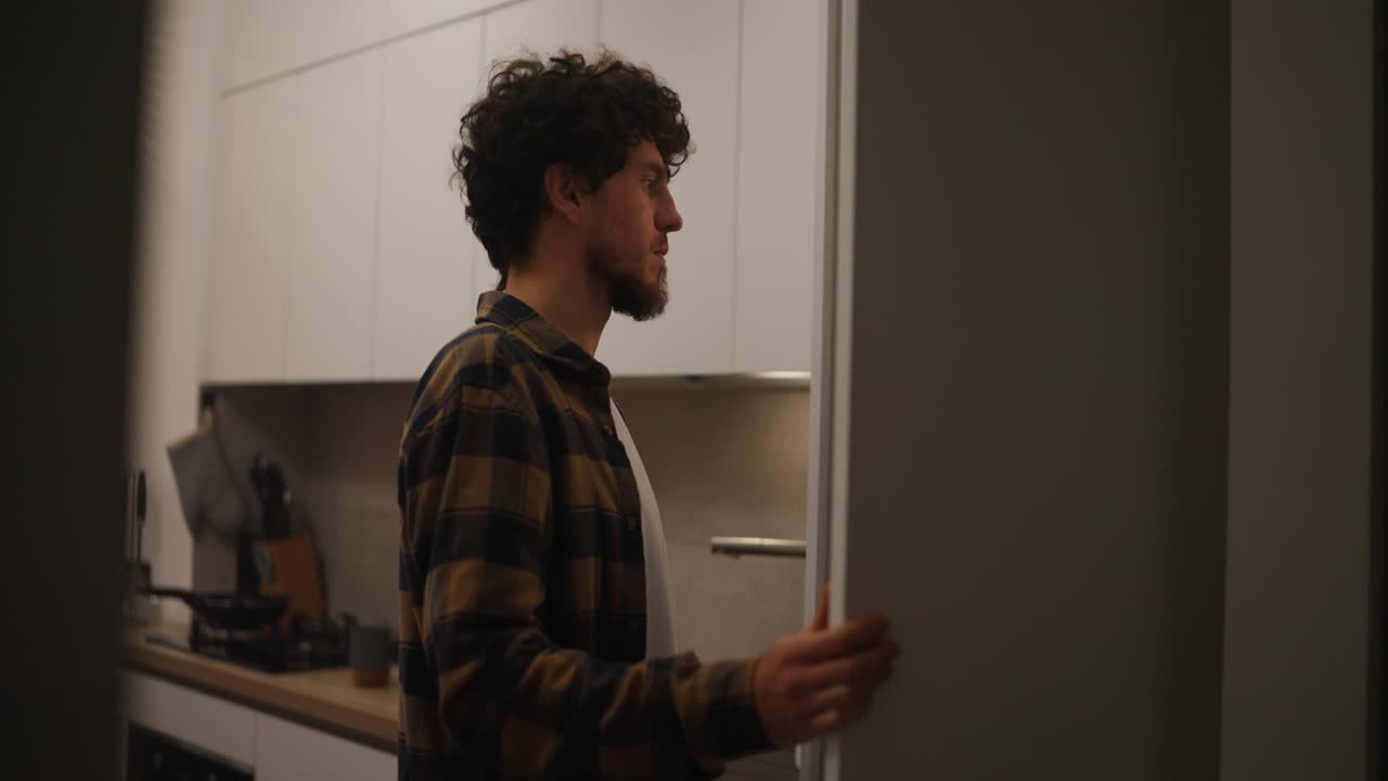 hombre mirando en el refrigerador en la cocina por la noche