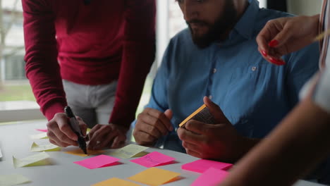 manager writing on sticky note on table.