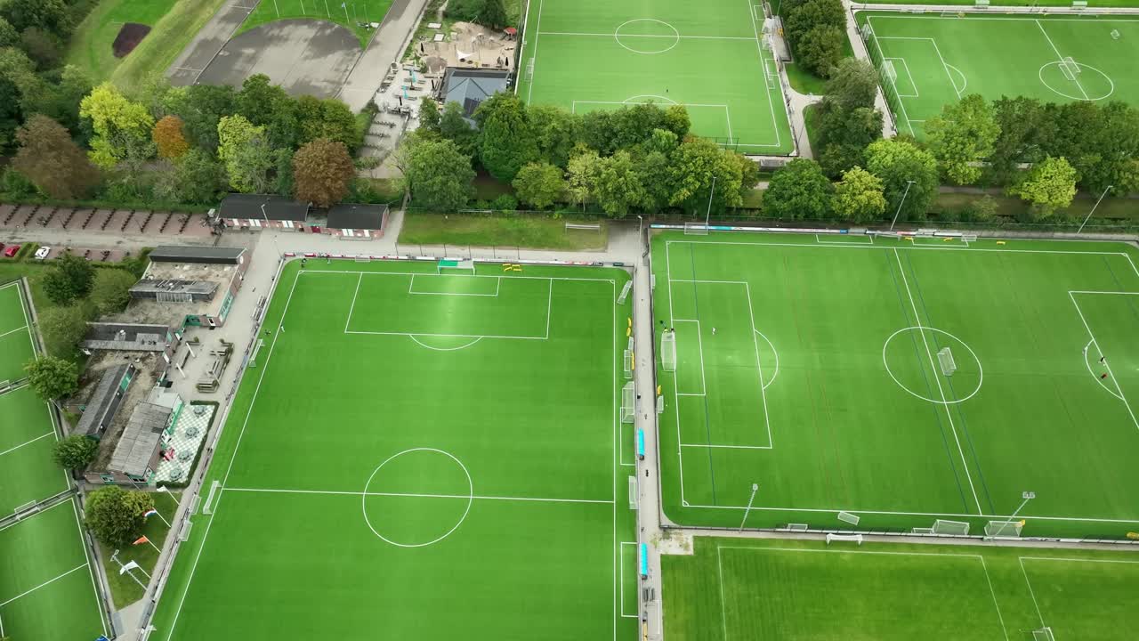 Big local sport complex with soccer fields in Netherlands, aerial pan down during daytime, local facilities for town