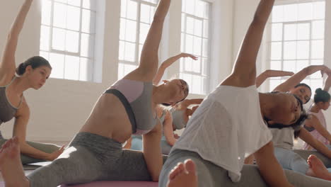 Clase-De-Yoga-De-Hermosas-Mujeres-Multiétnicas-Practican-Pose-De-Curvatura-Lateral-Sentada-Disfrutando-De-Un-Estilo-De-Vida-Saludable-Haciendo-Ejercicio-En-El-Gimnasio-Meditación-Grupal-Al-Amanecer