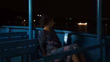 hermosa chica sentada en un barco durante la noche - disparo nocturno de una hermosa chica sentada sola en un barco de madera