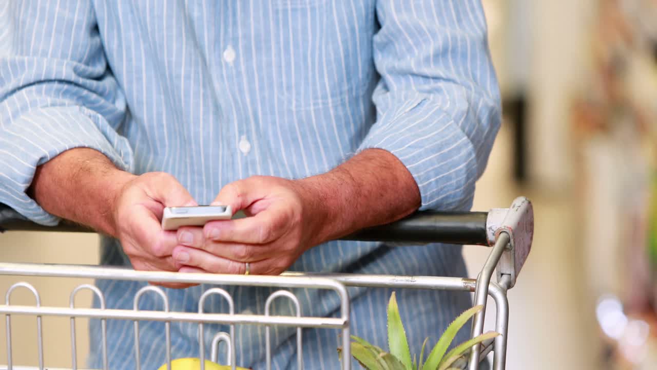 Uomo anziano che usa il telefono al supermercato.