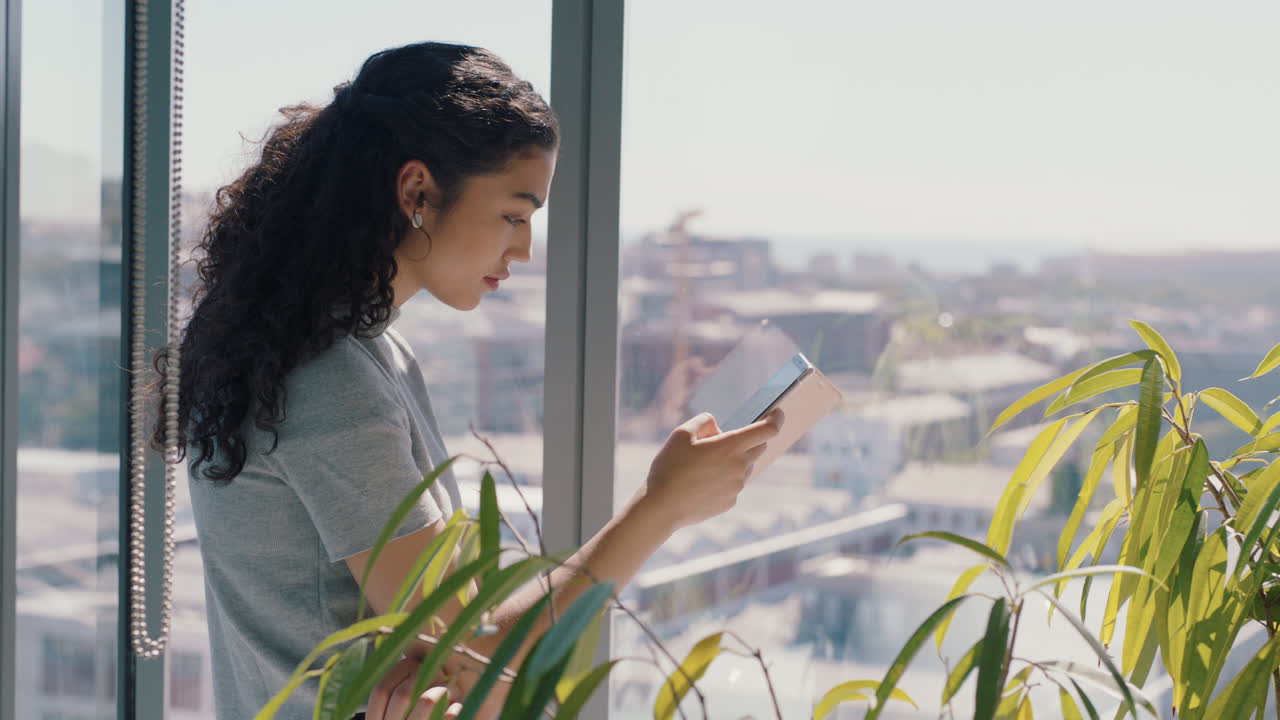 hermosa mujer de negocios usando un teléfono inteligente enviando mensajes de texto mujer ejecutiva chequeando correos electrónicos navegando mensajes en el teléfono móvil en la oficina de pie junto a la ventana con vista a la ciudad