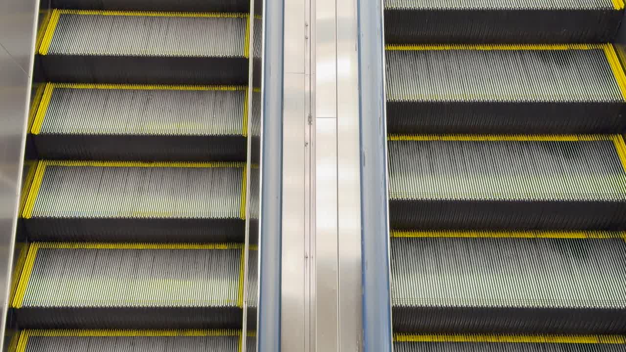 Statisk optagelse fra høj vinkel af tomme metalrulletrappetrin, der bevæger sig opad på en metrostation
