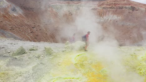 scenic view of couple walking trough volcano sulfuric smokes, tilt down camera toward crater