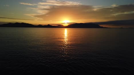 A-gorgeous-sunrise-by-the-ocean,-looking-at-the-coast-and-the-sun-from-a-boat