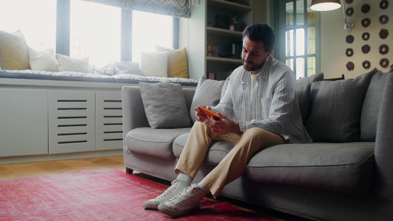 거실 의 소파 에 전화 를 사용하는 사람