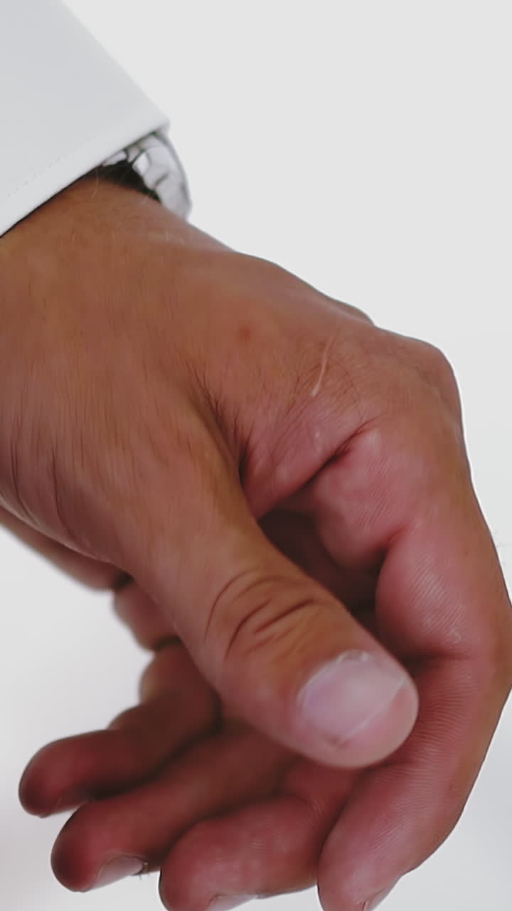 CU shot, slow motion: elegant young businessman in white shirt with cuff link holds hand on light background in modern office extreme close view