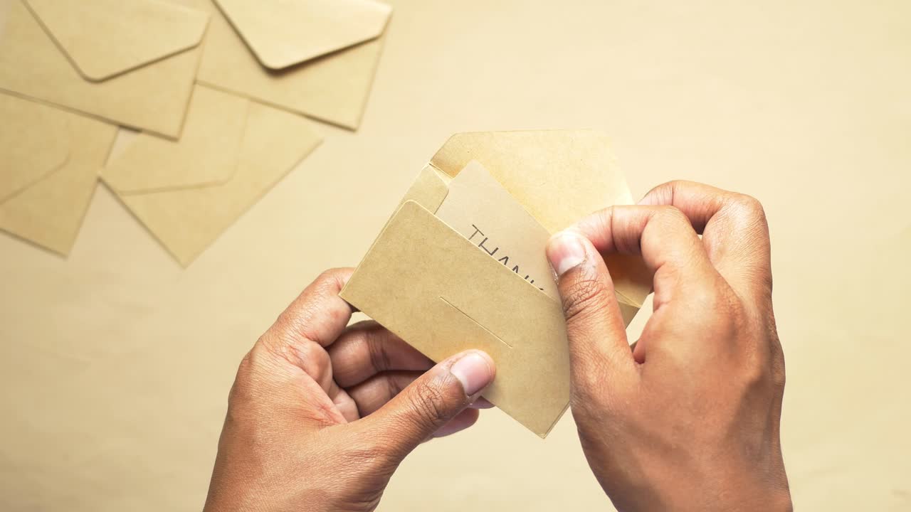 Hands Opening a Thank You Note Envelope