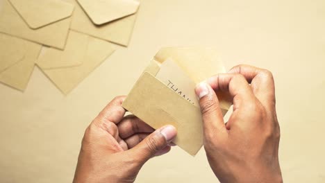 hands opening a thank you note envelope