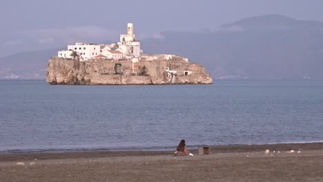 Mujer-En-La-Playa-De-Alhucemas,-Marruecos,-Con-La-Isla-Española-De-Alhucemas-Al-Frente