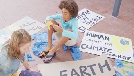 video of diverse boy and girl making protest placards in schoolyard, copy space