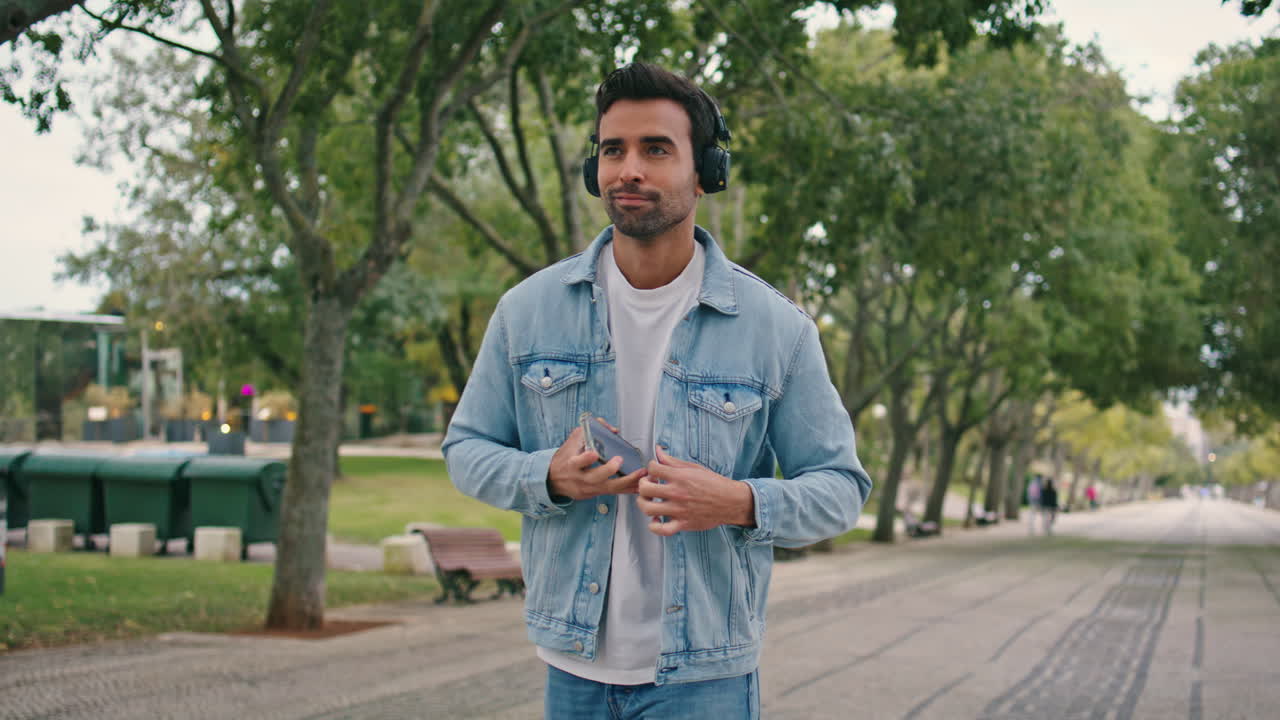 hombre con auriculares girando una aplicación de teléfono inteligente en una caminata de fin de semana. hombre escuchando música en el parque
