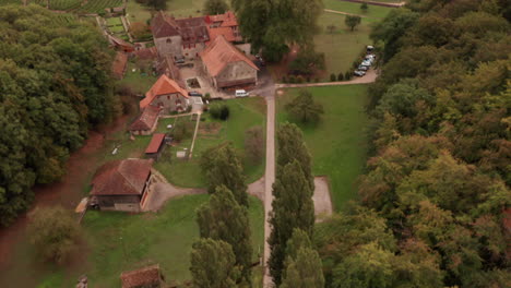 aerial of small road in countryside, tilting up to reveal old buildings near lake