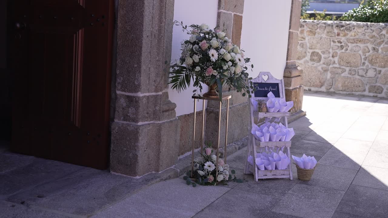 Ingresso di una chiesa decorato con una composizione floreale e coni di petali per un matrimonio